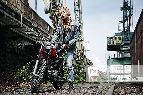 Porträt einer selbstbewussten jungen Frau  die auf ein Motorrad steigt