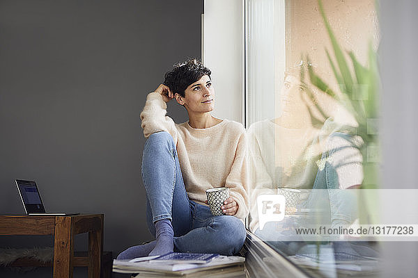 Entspannte Frau zu Hause am Fenster sitzend