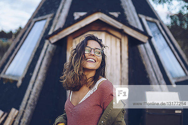 Porträt einer lachenden jungen Frau vor einem finnischen Haus