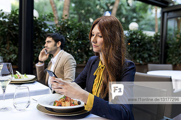 Mann und Frau benutzen Mobiltelefone in einem Restaurant