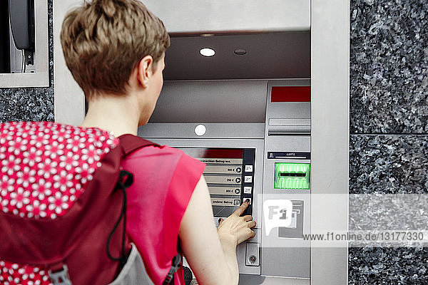 Rückansicht einer Frau am Geldautomaten