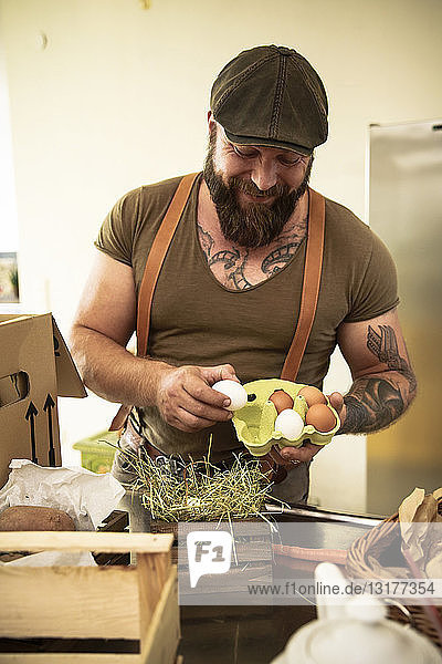 Reifer Mann mit Lieferservice prüft Eier  bevor sie in Kartons verpackt werden