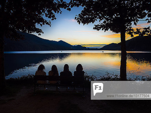 Austria  Upper Austria  Salzkammergut  Lake Fuschlsee  people sitting on bench enjoying sunset