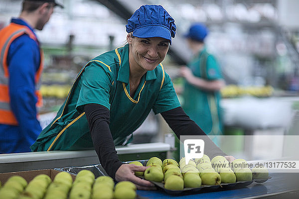 Porträt einer lächelnden Frau  die in einer Apfelfabrik arbeitet