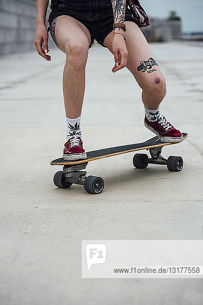 Beine einer jungen Frau  die auf einer Promenade Carver-Skateboard fährt