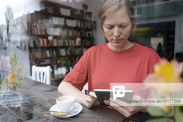 Junge Frau mit Tablette am Fenster in einem Cafe