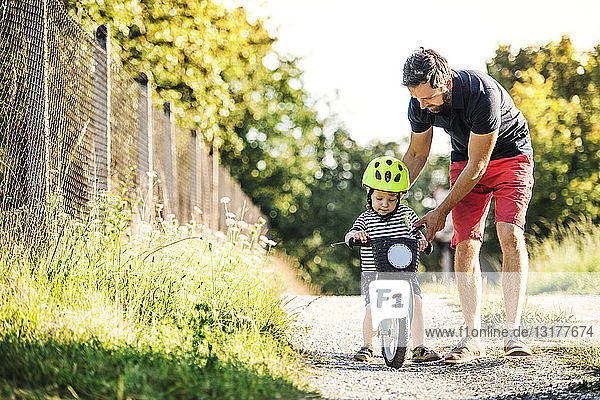 Father teaching little son riding bicycle