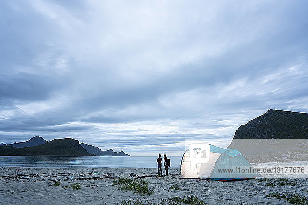 Norwegen  Lappland  Zwei Personen im Zelt an einem Strand am Fjord
