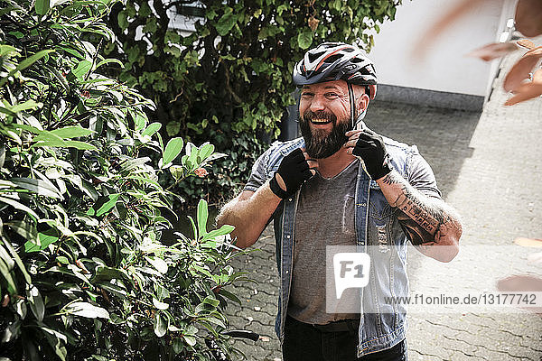 Porträt eines lachenden Mannes  der einen Fahrradhelm aufsetzt