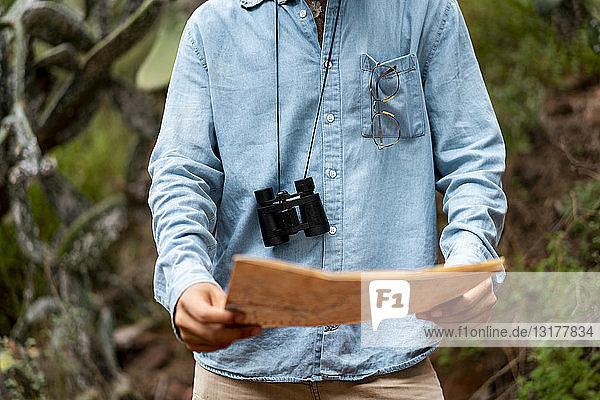Young man standing in nature  looking at map