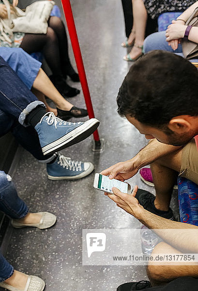UK  London  man in underground train looking at cell phone