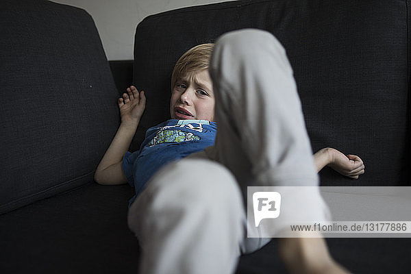 Porträt eines traurigen Jungen auf der Couch liegend