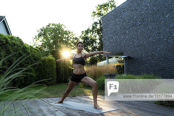 Frau praktiziert Yoga im Garten