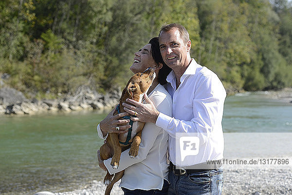 Mature couple with a dog at the river Isar  Upper Bavaria  Germany