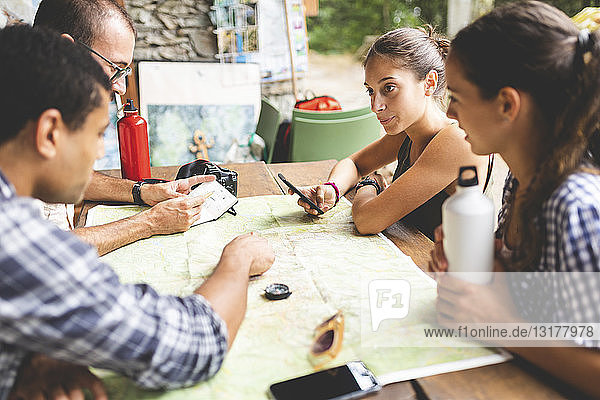 Gruppe von Wanderern sitzt zusammen und plant eine Wanderroute mit Blick auf die Karte