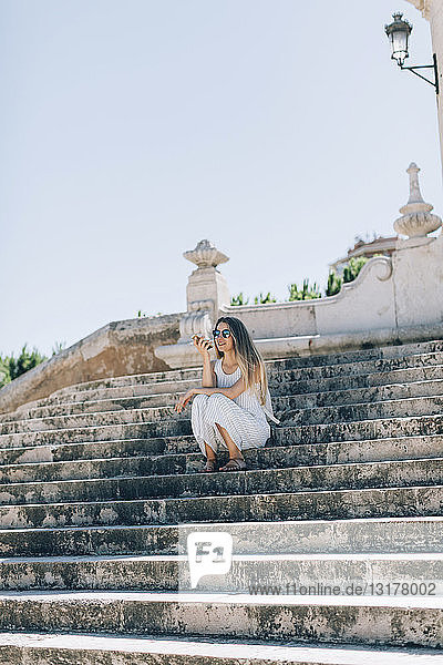 Spanien Valencia Frau sitzt auf einer Treppe und benutzt ein Smartphone