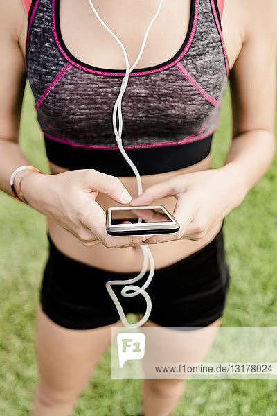 Teenage girl using smartphone and earphone on race track