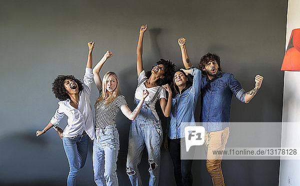 Group portrait of friends standing at a wall cheering