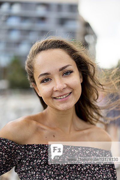 Porträt einer lächelnden schönen jungen Frau mit windgepeitschtem Haar