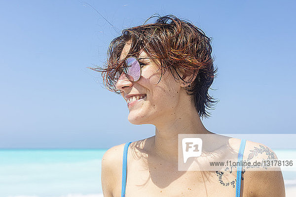 Porträt einer leseköpfigen Frau mit Sonnenbrille am Meer