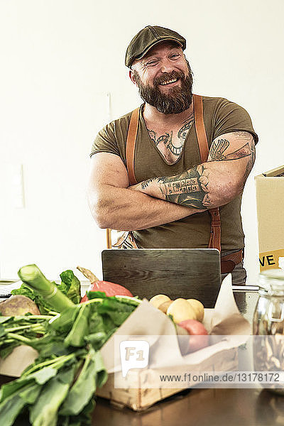 Besitzer eines Lieferdienstes für Bio-Gemüse  der stolz in seiner Küche steht