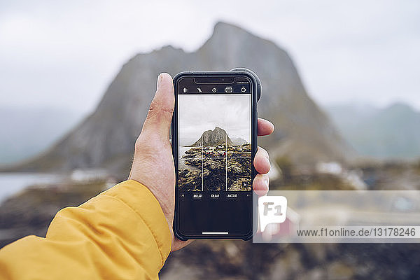Norwegen  Lofoten  Hamnoy  Smartphone zum Fotografieren in der Hand
