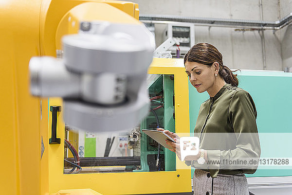 Geschäftsfrau prüft Industrieroboter in High-Tech-Unternehmen