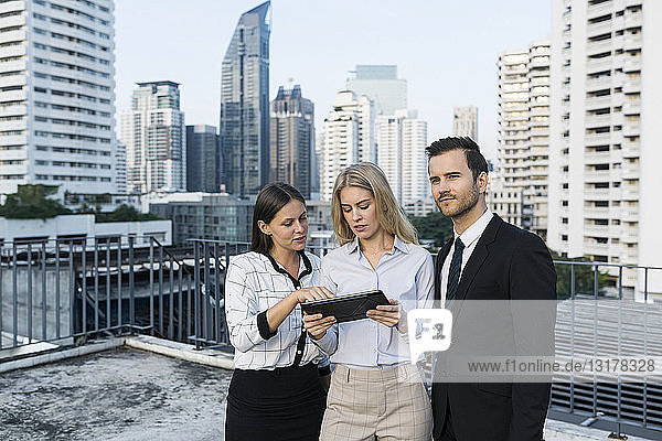 Colleagues with tablet on city rooftop