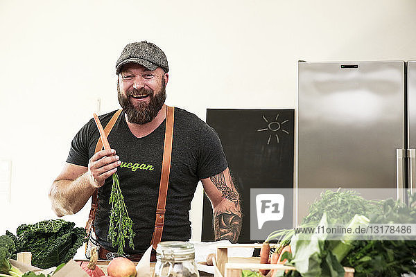 Veganer hält Karotte in seiner Küche
