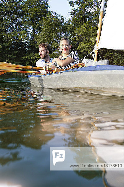 Junges Paar geniesst eine Kanufahrt mit Segeln auf einem See