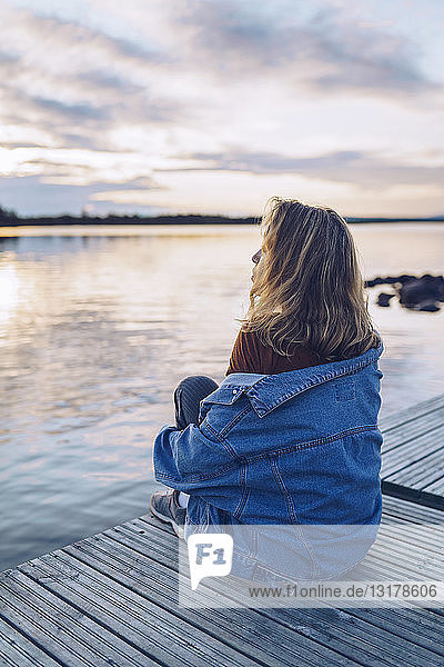 Junge Frau sitzt am Inari-See und schaut auf Aussicht  Finnland