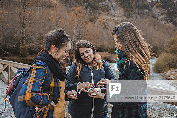Spanien  drei junge Frauen betrachten Sofortbilder auf einer Brücke im Ordesa-Nationalpark