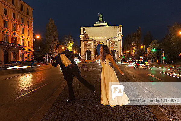 Glückliches Brautpaar überquert nachts die Leopoldstraße in München
