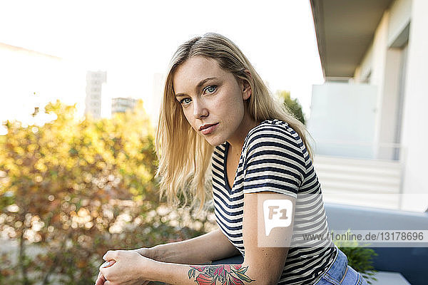 Porträt einer blonden jungen Frau auf dem Balkon