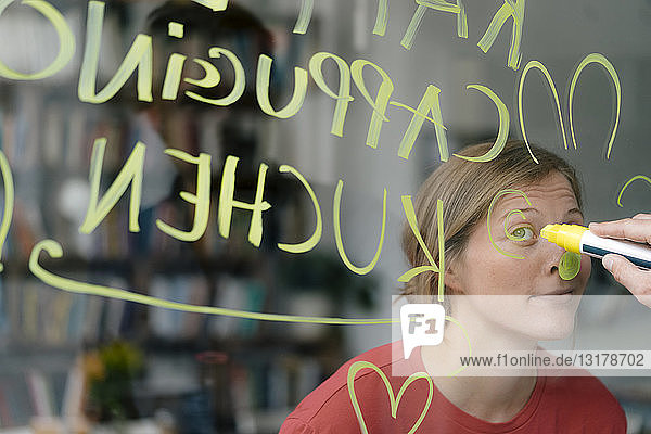 Porträt einer jungen Frau hinter einer Fensterscheibe in einem Cafe mit Handschrift