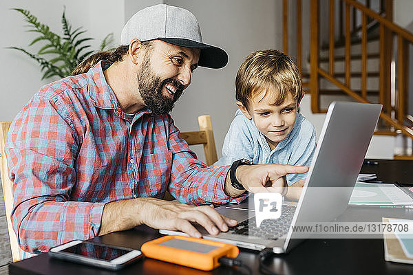 Vater und Sohn benutzen gemeinsam einen Laptop