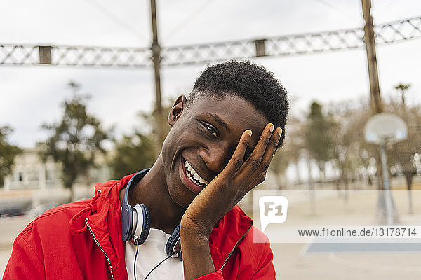 Porträt eines jungen schwarzen Mannes  lachend mit der Hand im Gesicht