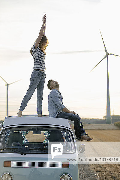 Glückliches Paar auf dem Dach eines Wohnmobils in ländlicher Landschaft