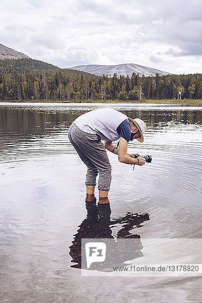 Schweden  Lappland  Mann steht im Wasser und fotografiert