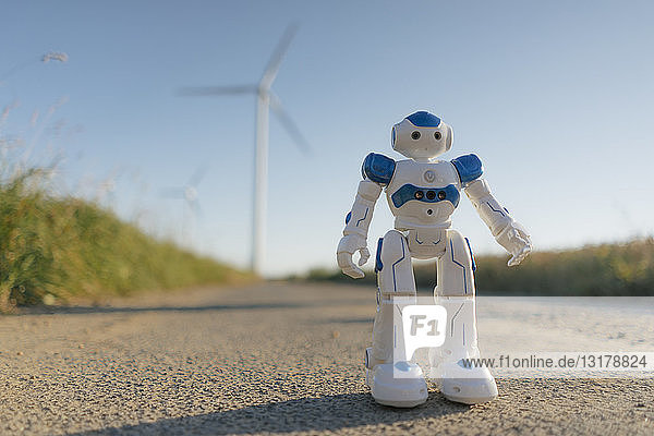 Roboter steht auf einem Feldweg in einem Windpark