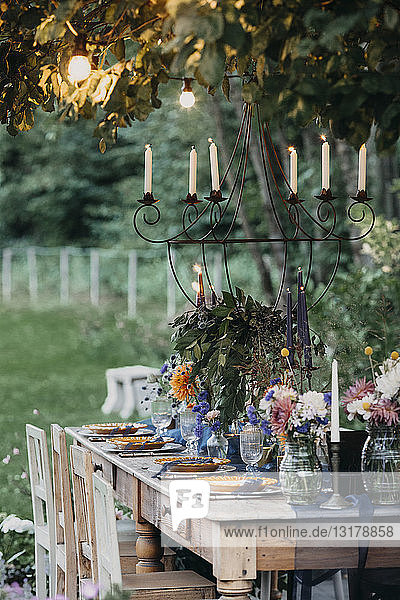 Festlich gedeckter Tisch mit Kerzen unter einem Baum