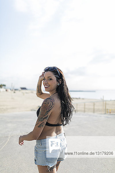 Portrait of smiling young woman with nose piercing and tattoos on the way to the beach