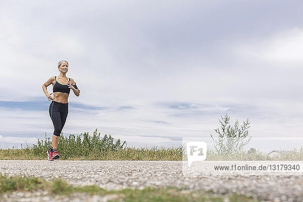 Reife Frau rennt im Sommer auf abgelegenem Feldweg