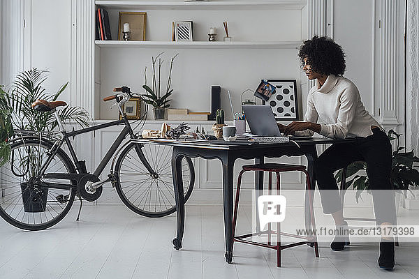 Mittlere erwachsene Frau  die in ihrem Heimbüro arbeitet und einen Laptop benutzt