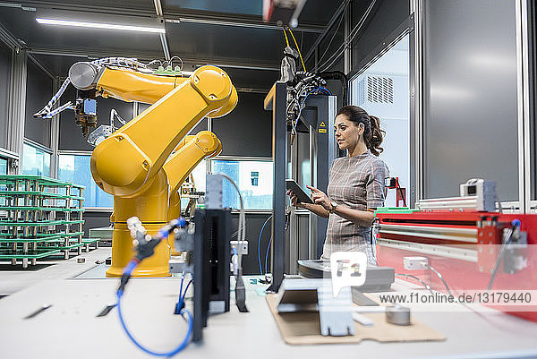Geschäftsfrau prüft Industrieroboter in High-Tech-Unternehmen