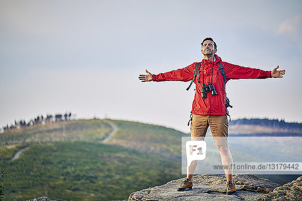 Man standing with outstretched arms on mountain top