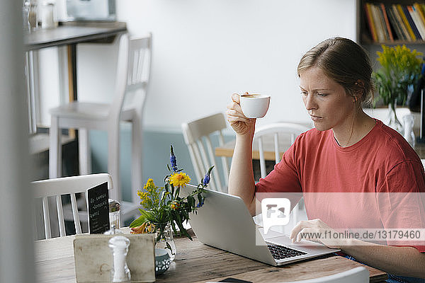 Junge Frau mit Laptop am Tisch in einem Café