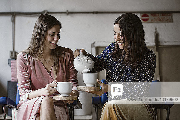Two friends drinking tea together in a loft