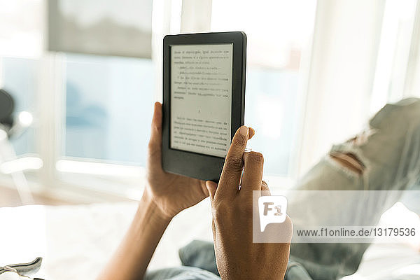 Nahaufnahme einer Frau  die im Bett liegt und ein E-Book liest