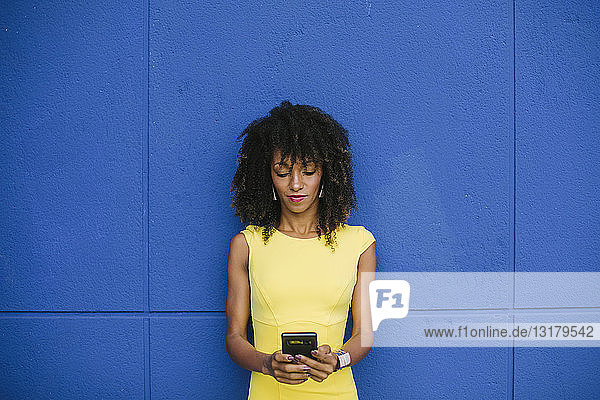 Porträt einer modischen Geschäftsfrau in gelbem Kleid mit Textnachrichten vor blauem Hintergrund